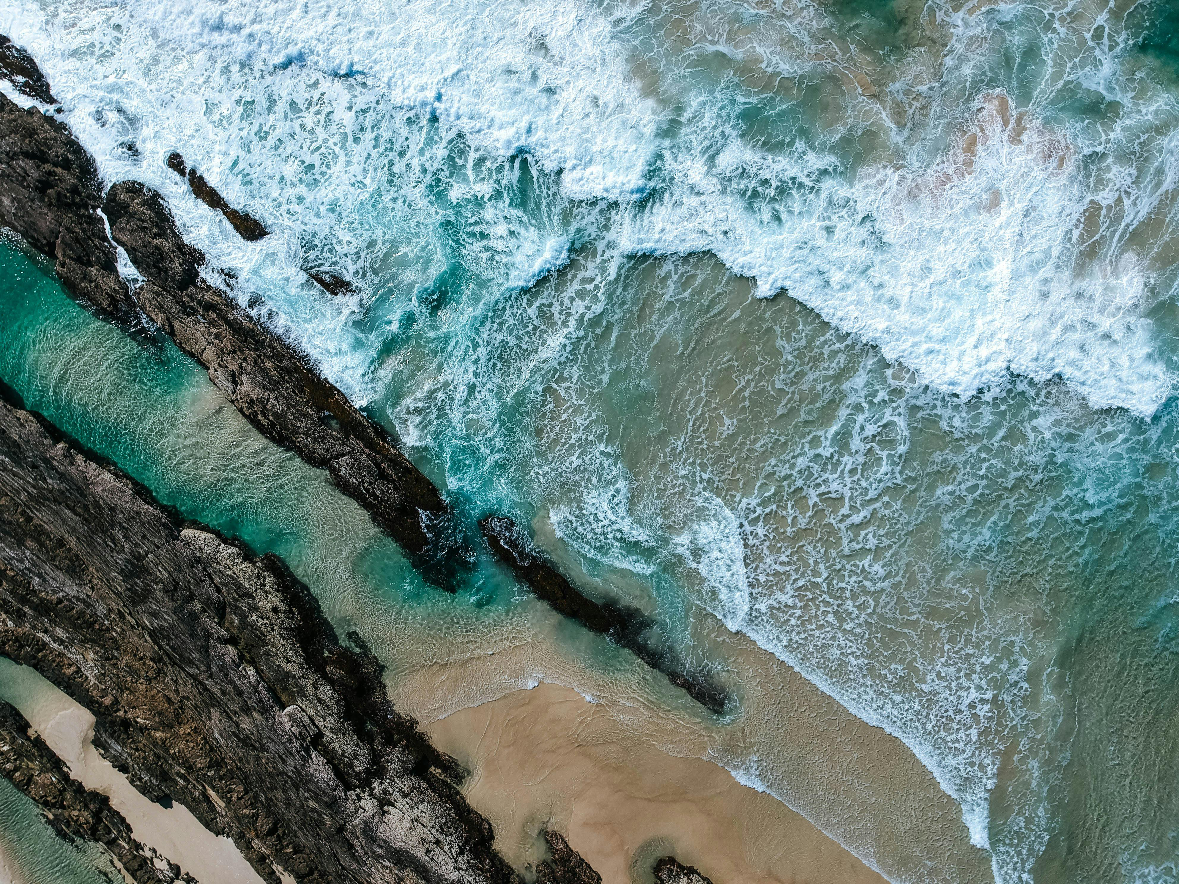 Overhead view of blue ocean waves over rocks